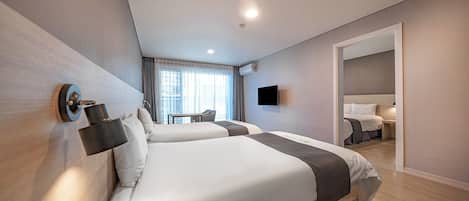 A modern hotel room with two beds, a desk, a flat-screen TV, and a large mirror.