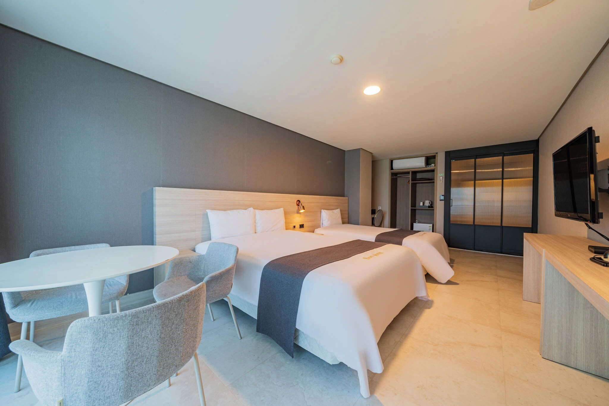 Ein modernes Hotelzimmer mit zwei Betten, einem Schreibtisch und einer Sitzecke.