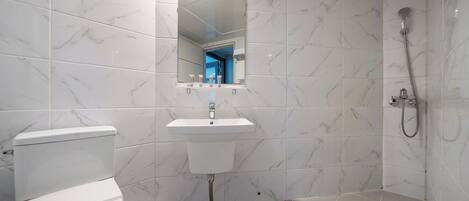 Un baño moderno con inodoro, lavamanos y ducha.