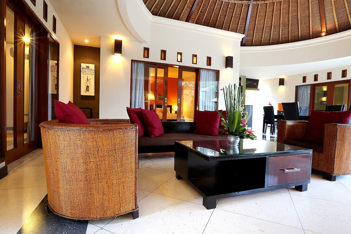 A spacious lobby with a sofa, a coffee table, and a wicker chair.