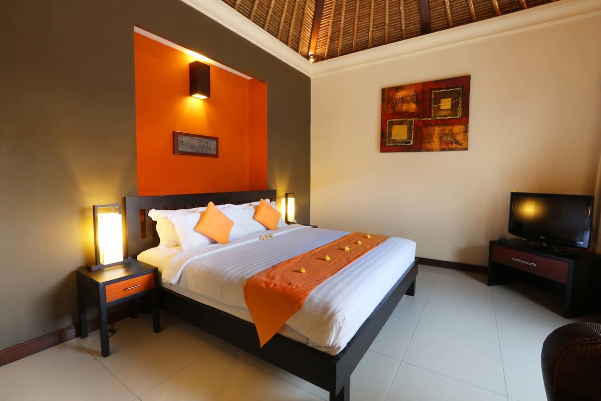 A hotel room with a bed, nightstands, a television, and a decorative wall piece.