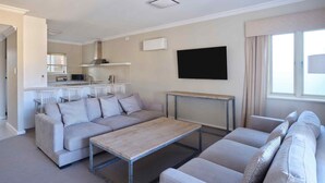 Una sala de estar moderna con un conjunto de sofá, una mesa de centro y un televisor montado en la pared.
