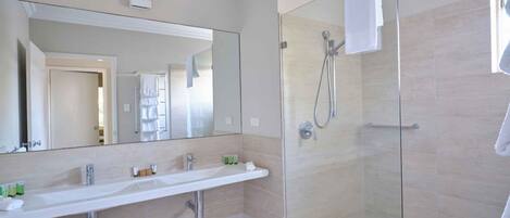A modern bathroom with a large mirror, a sink, and a shower.
