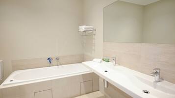 A modern bathroom with a large bathtub, a double sink, and a mirror.