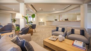 Un moderno hall de hotel con sofás, un mostrador de recepción y una mesa de centro.