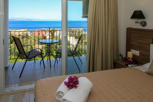 A hotel room with a balcony, a bed with a towel and flowers, a table with chairs, and a view of the sea. - Hotel Yannis Corfu (Corfu)