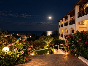 A building with multiple balconies overlooking a coastal area at night. - Hotel Yannis Corfu (Corfu)