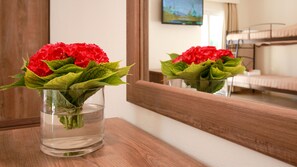 A clear glass vase with red flowers on a wooden surface. - Hotel Yannis Corfu (Corfu)