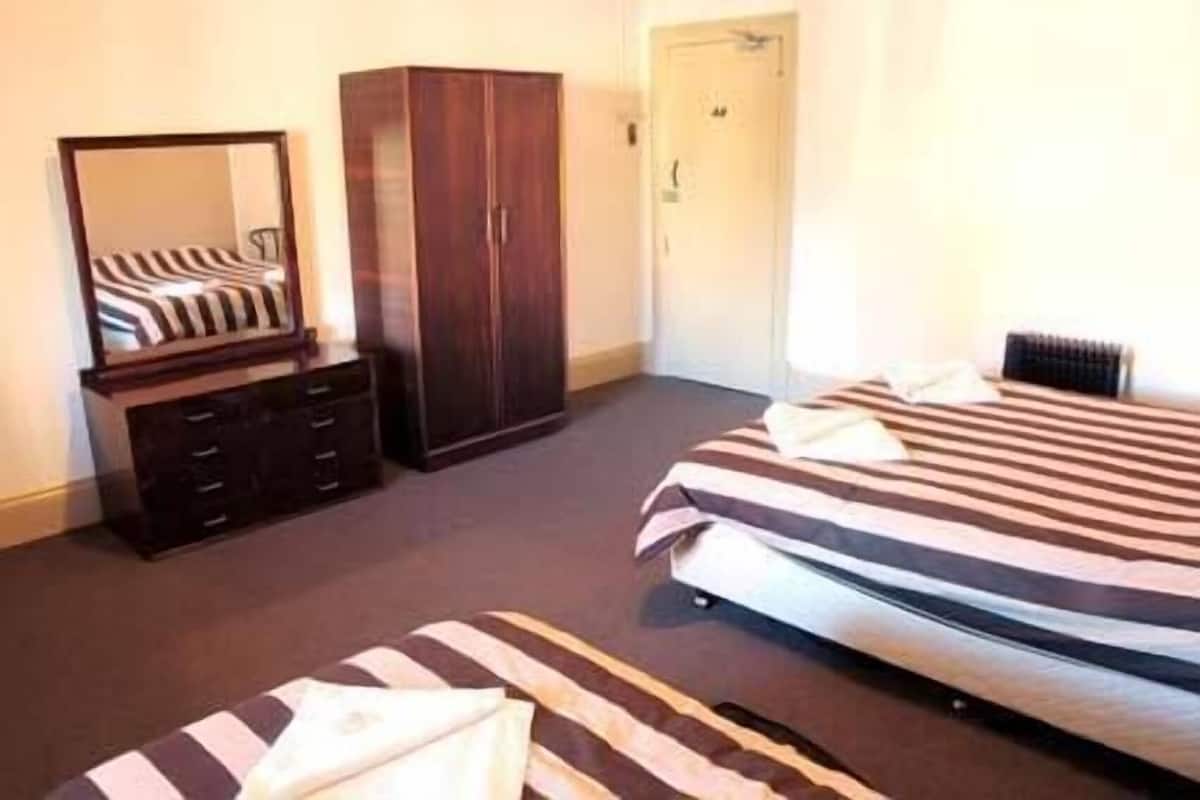 A bedroom with a bed, a wardrobe, and a mirror.
