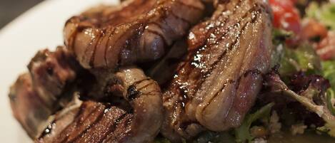 A plate of grilled meat with a side salad and a glass of beer.