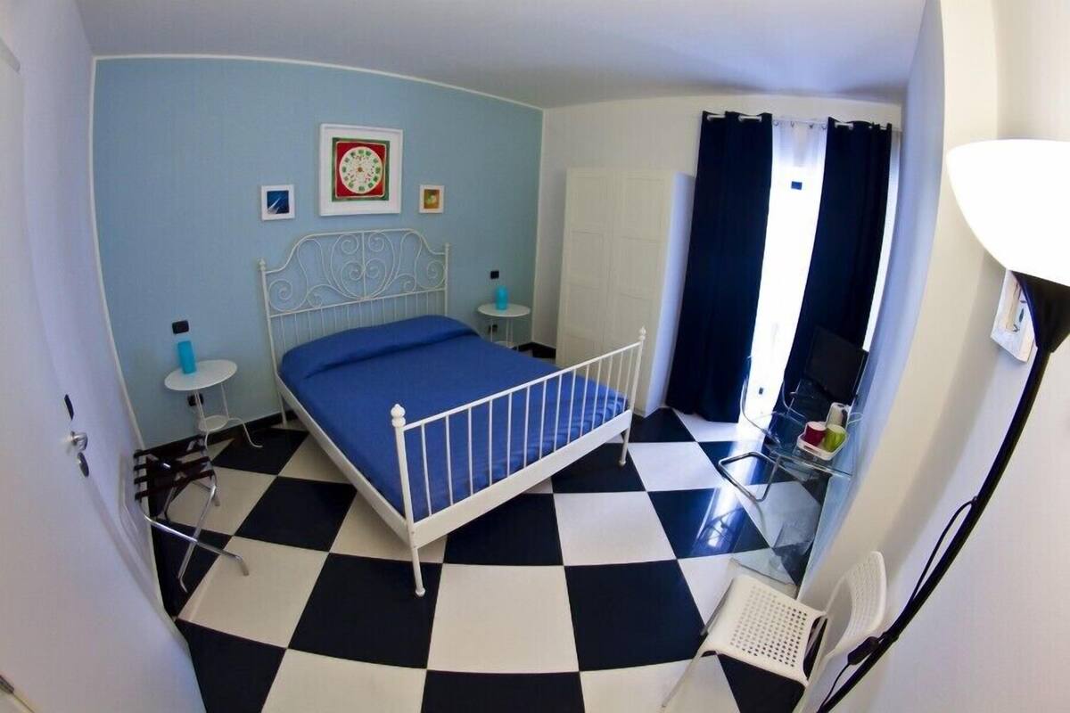 A room with a bed, a small table, a chair, and a window with curtains.