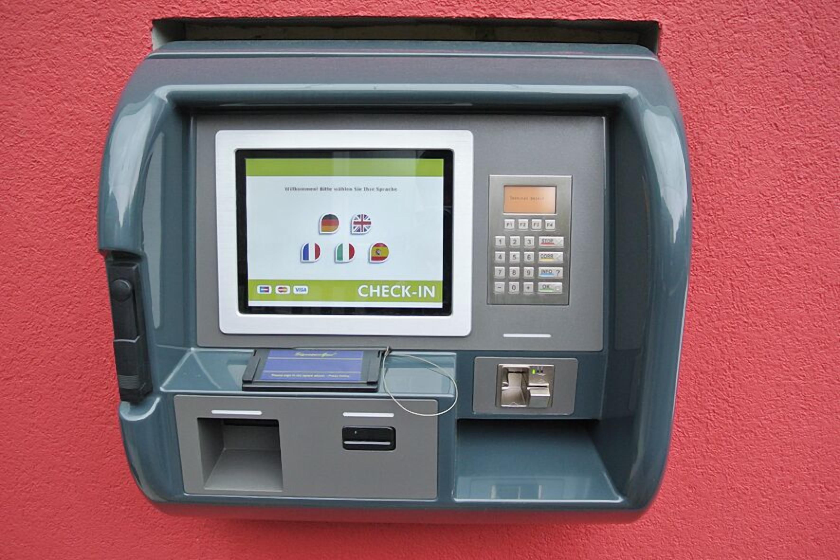 A self-service check-in kiosk with a screen displaying multiple language options and a keypad.