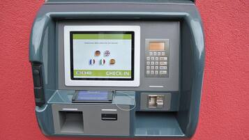 A self-service check-in kiosk with a screen displaying multiple language options and a keypad.