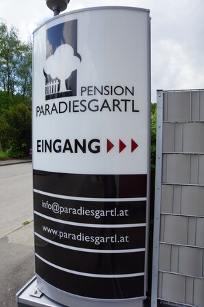 A sign for Pension Paradiesgartl with contact information and arrows indicating direction. - Pension Paradiesgartl (Amstetten)