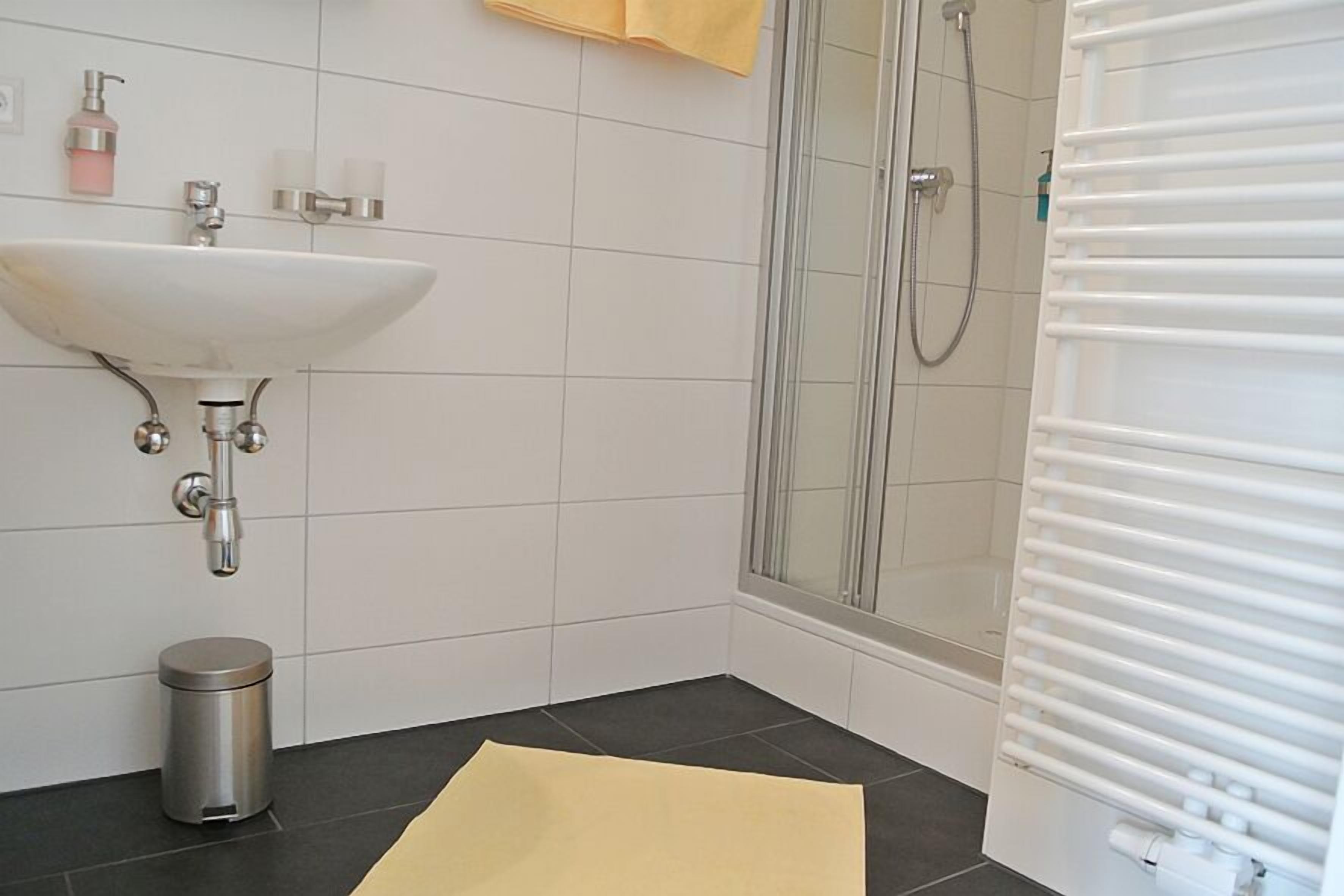Et badeværelse med håndvask, toilet og bruser.