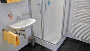 A bathroom with a white sink, glass shower enclosure, and a towel rack.