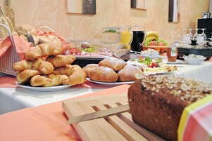 Un bufé de desayuno con panes, pasteles, frutas y bebidas variadas.