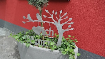A concrete planter with a metal tree sculpture and the word "Wich" partially visible.
