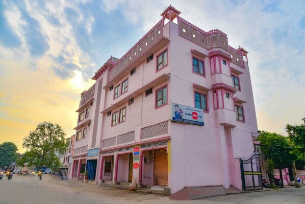 A pink multi-story building with a sign for 'Hotel Jaisnagar Palace'.