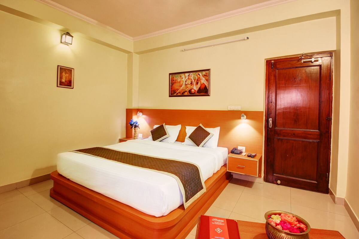 Een hotelkamer met een groot bed, nachtkastjes, een houten deur en kunst aan de muur.