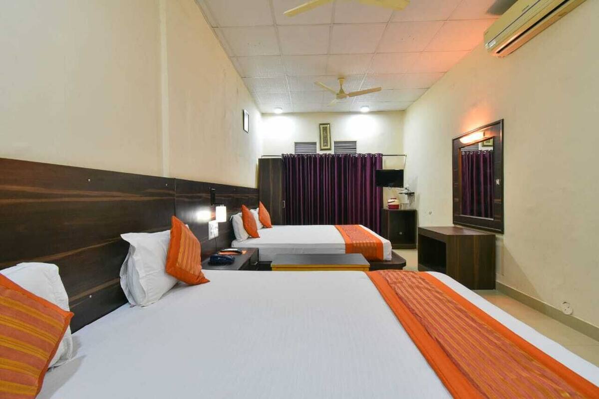Een hotelkamer met twee bedden, een plafondventilator, een televisie en een spiegel.