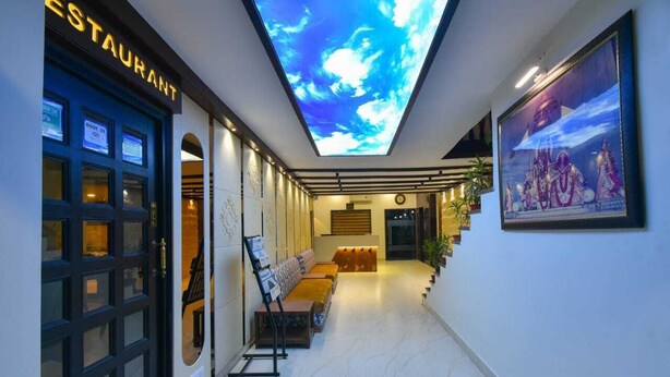 Vestíbulo de hotel con diseño moderno, que incluye un techo con cielo digital, zona de estar y letrero de restaurante.
