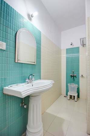A bathroom with a pedestal sink, a mirror, and a toilet.