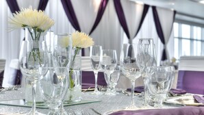 A table set with clear glassware, purple napkins, and white flowers in a glass vase. - Hotel Clique Calgary Airport (Calgary)