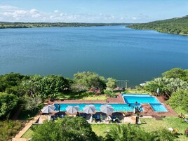 Un área de piscina con varias piscinas, rodeada de exuberante vegetación y vistas a una gran extensión de agua.