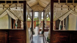 A corridor leading to a room with a canopy bed, wooden walls, and a view of the outdoors. - Naara Ecolodge & Spa (Chidenguele)