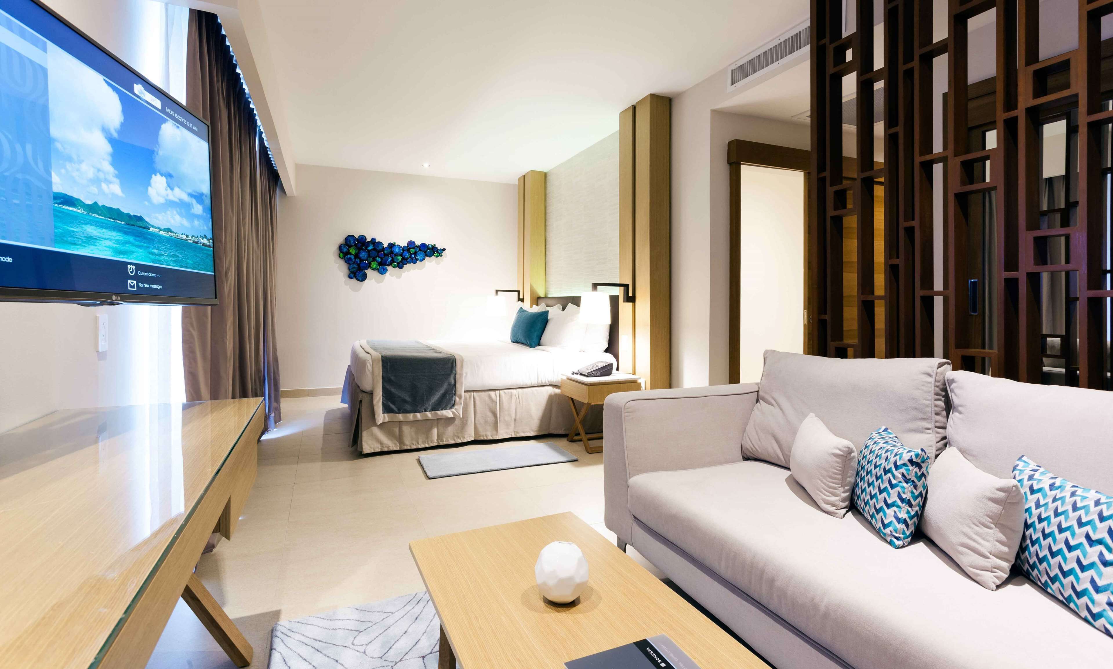 Et moderne hotelværelse med seng, sofa, tv og en dekorativ vægdekoration.