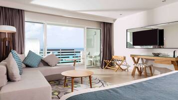 Una habitación de hotel moderna con una cama grande, un sofá, un escritorio y un balcón con vistas al mar.