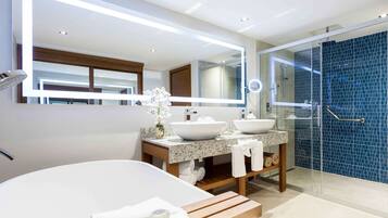 Un baño moderno con una bañera grande, dos lavamanos, ducha con mampara de vidrio y tocador con espejo.