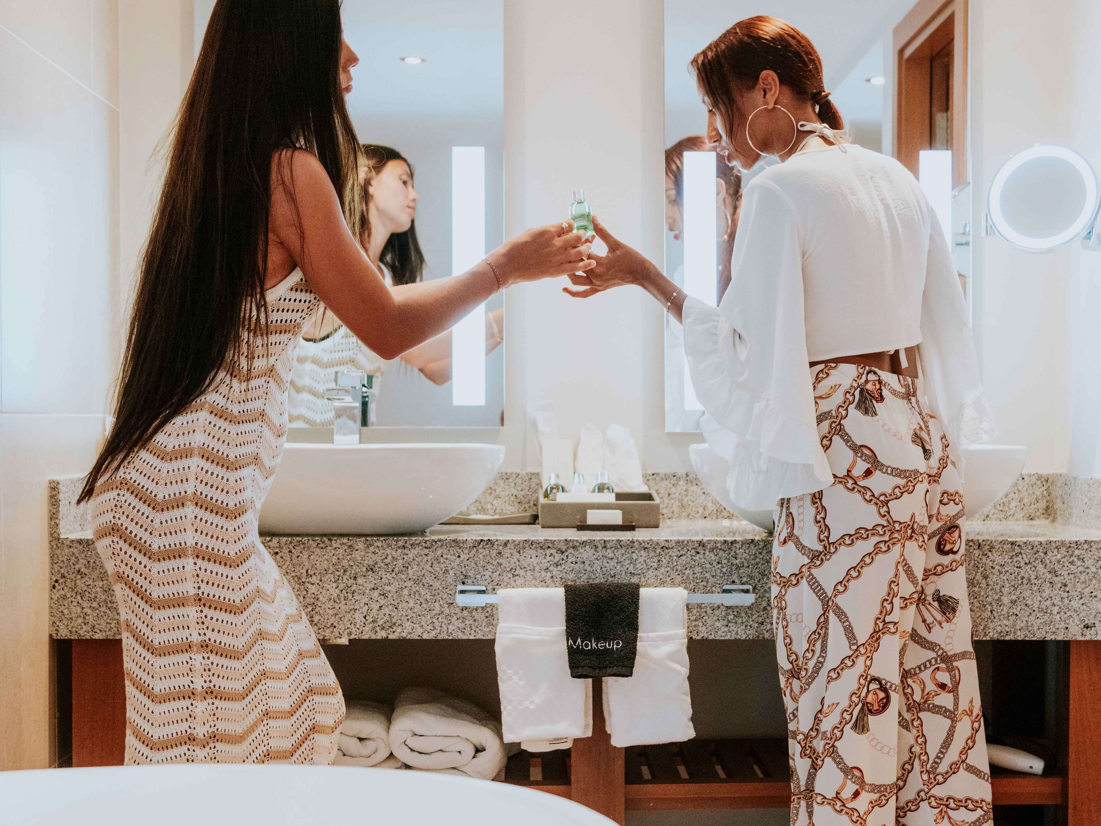 A modern bathroom with a large mirror, a sink, and a vanity. There are towels and toiletries visible.