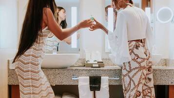 A modern bathroom with a large mirror, a sink, and a vanity. There are towels and toiletries visible.