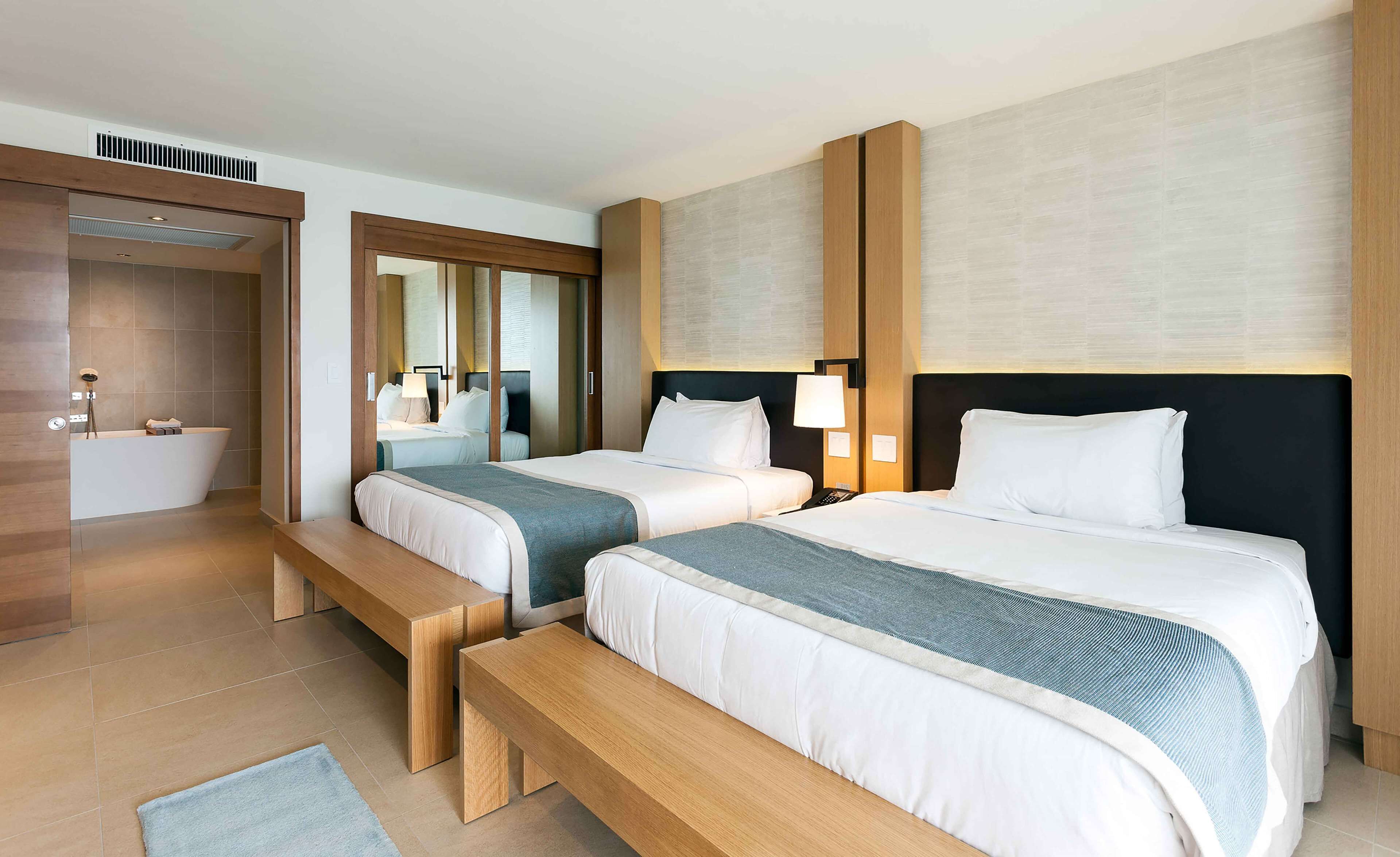 A hotel room with two beds, a bathroom, and a sitting area.