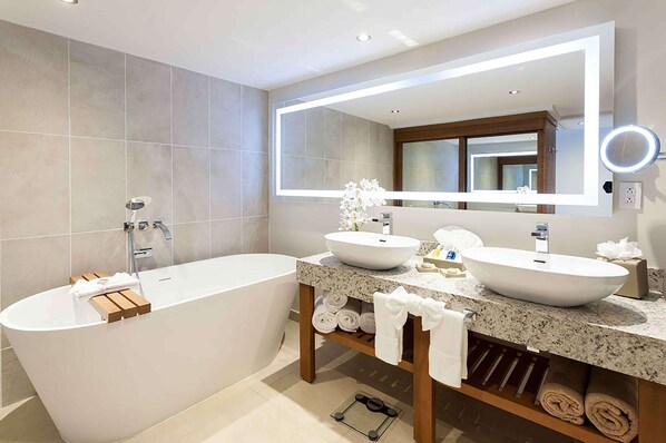 Une salle de bain moderne avec une baignoire sur pieds, deux vasques, un meuble-lavabo avec un miroir et un porte-serviettes.
