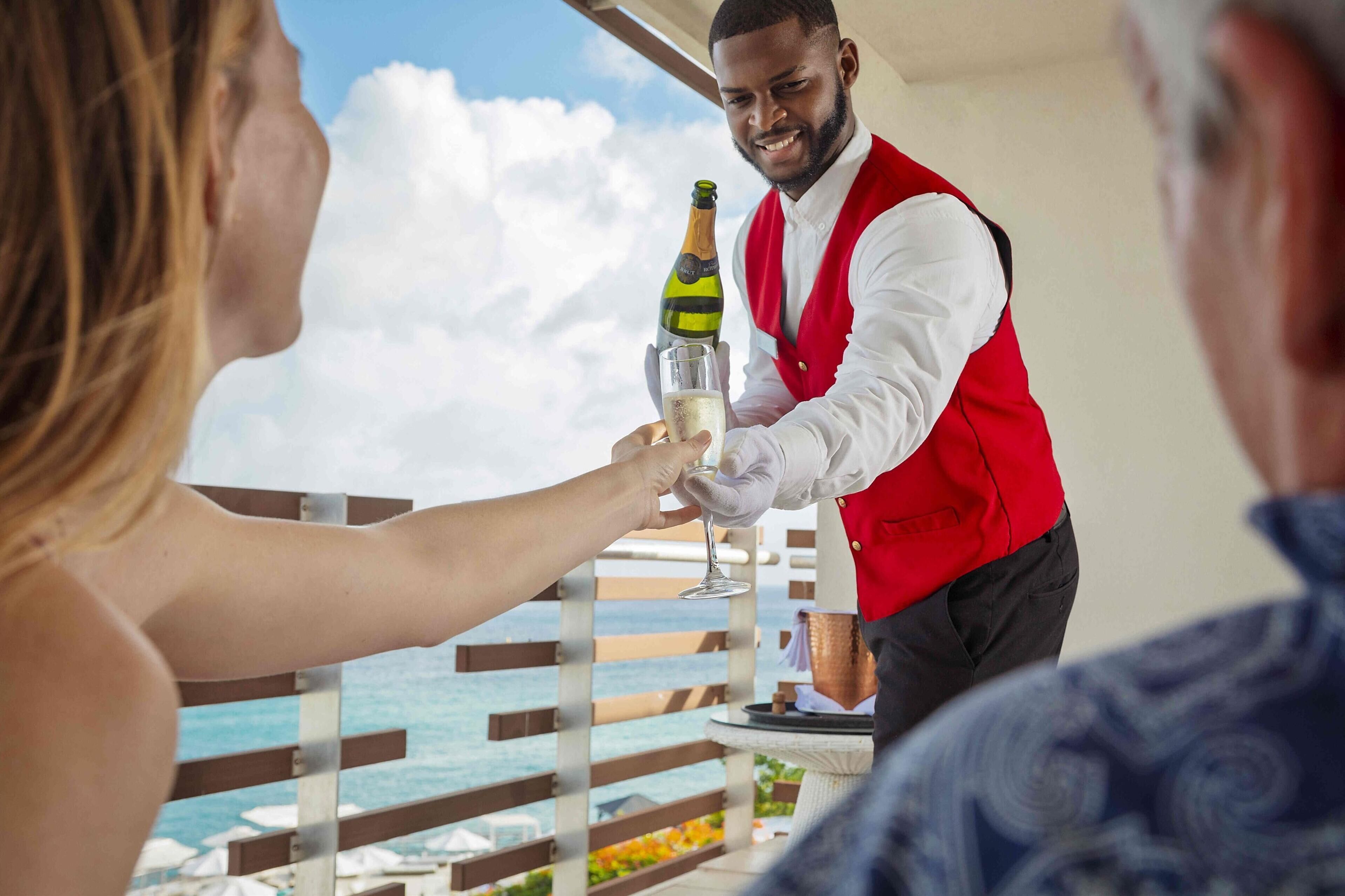 A person in a red vest pouring a drink into a glass.