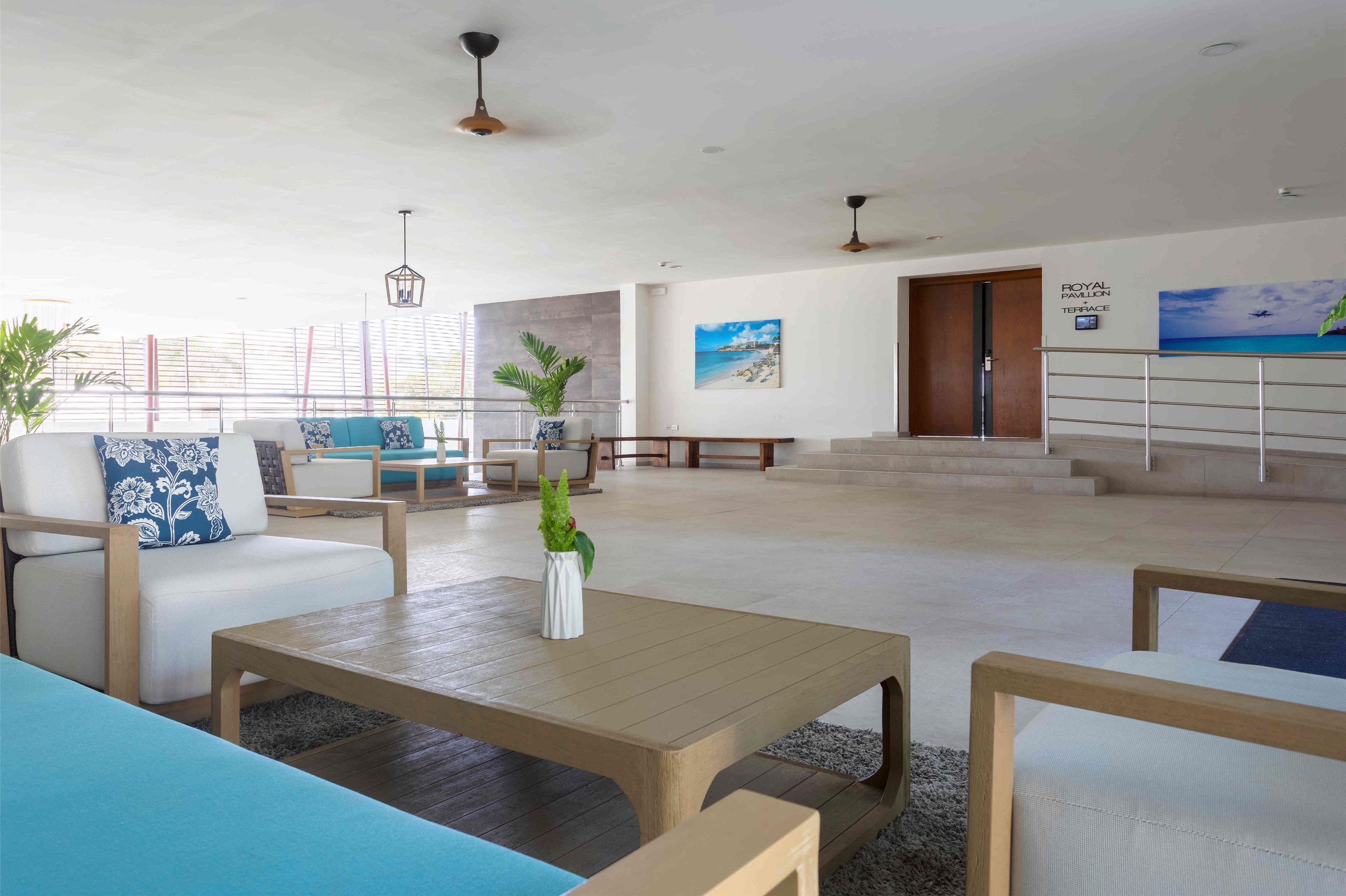 A spacious lobby with a seating area, a staircase, and a view of the beach.