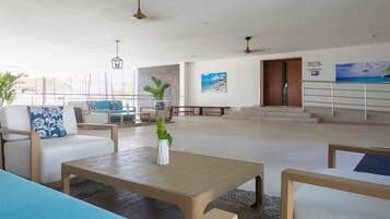 A spacious lobby with a seating area, a staircase, and a view of the beach.