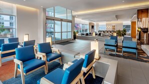 A modern hotel lobby with blue seating, a bar area, and large windows offering city views. - Hyatt House Salt Lake City Downtown (Salt Lake City)