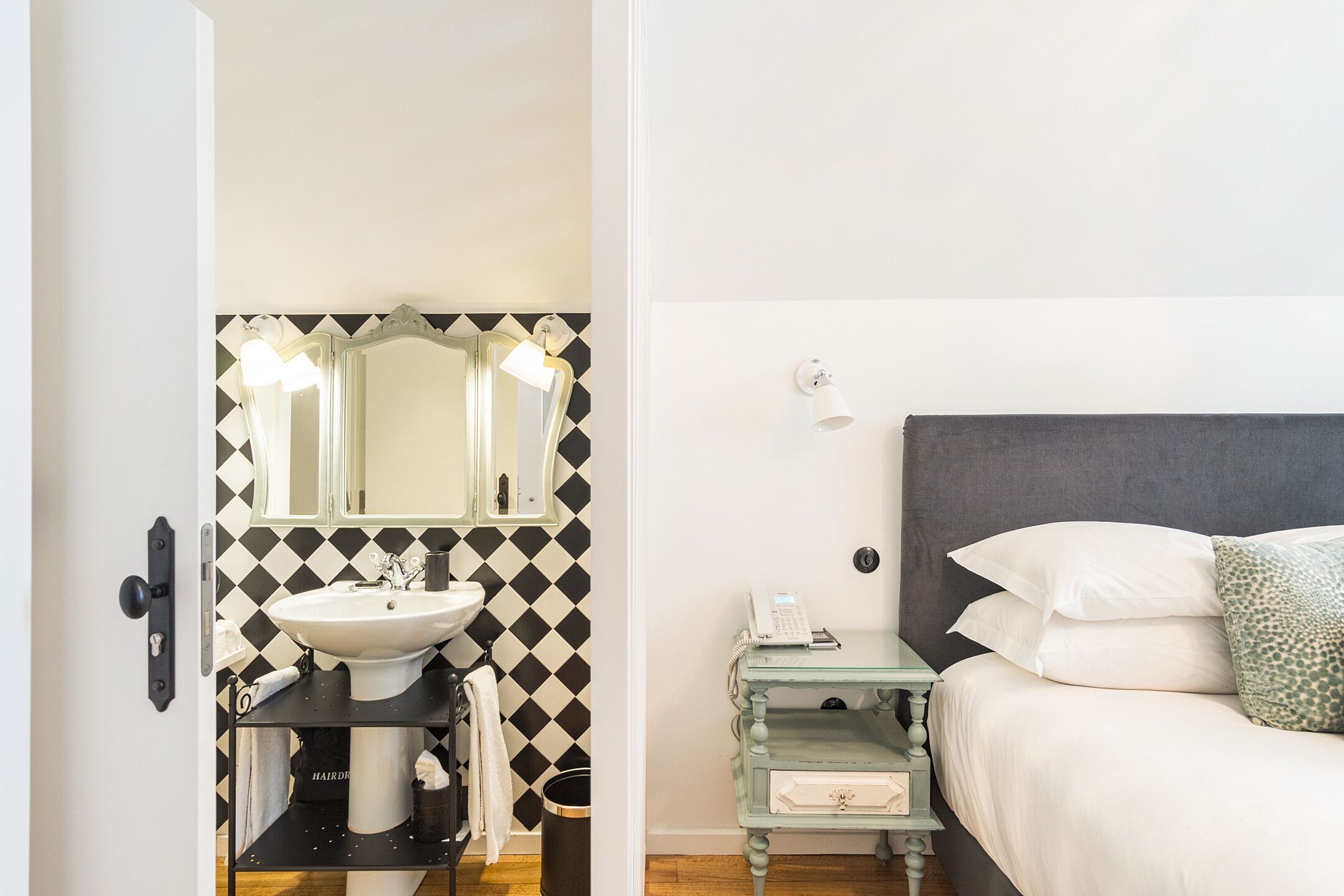 A bathroom with a sink, mirror, and a small table with a phone.