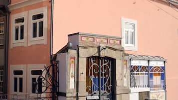 A building with a pink facade, a tiled roof, and a gated entrance with a decorative archway.