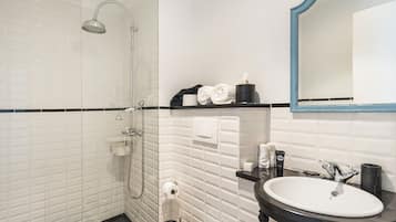 Un baño moderno con ducha de vidrio, un lavabo blanco y un espejo con marco azul.