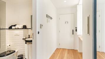 Une salle de bain moderne avec un carrelage noir et blanc à motifs, des toilettes blanches et un lavabo surmonté d’un miroir.