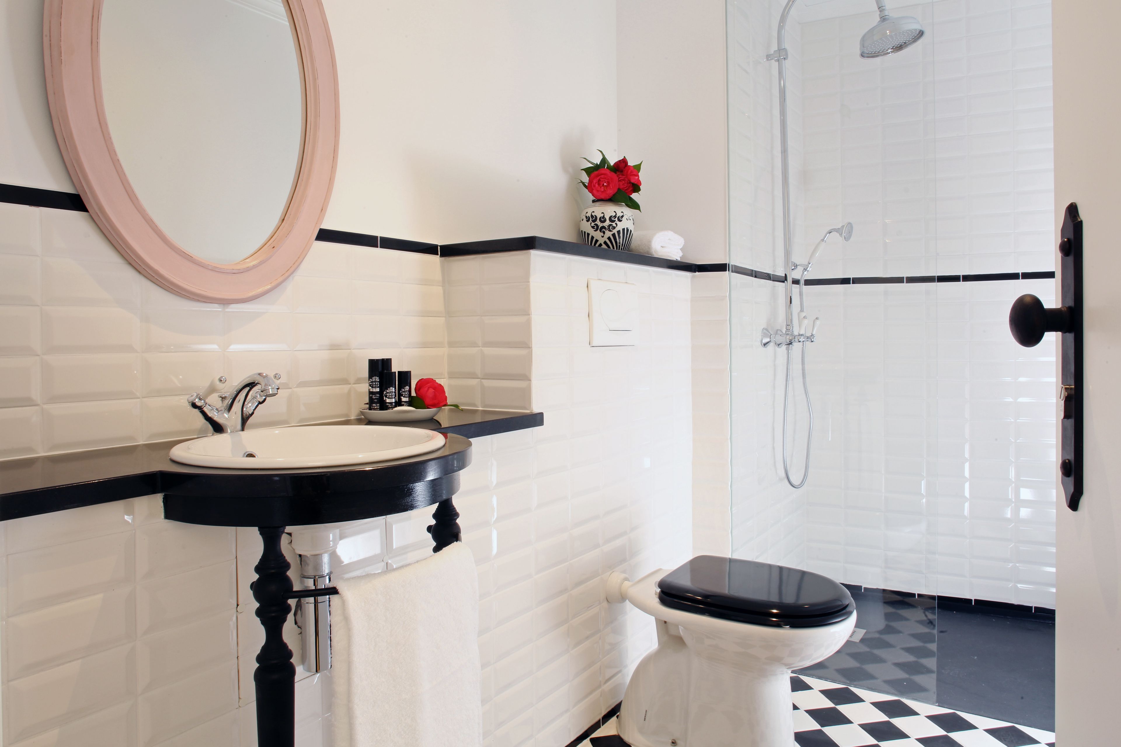 A bathroom with a white sink, black countertop, and a toilet. There is a shower with a glass door and a mirror above the sink.