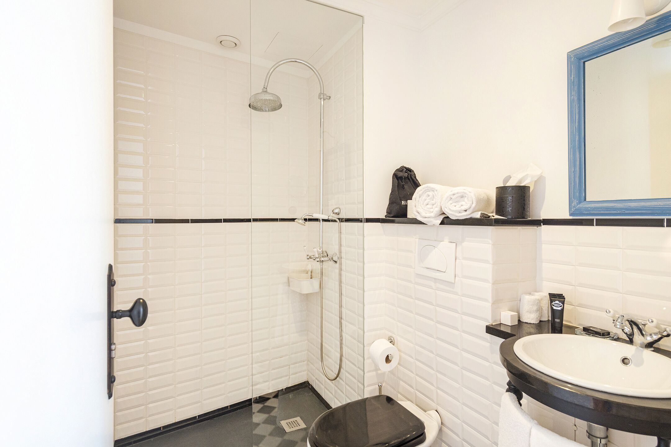 A bathroom with a shower, toilet, sink, and a mirror.