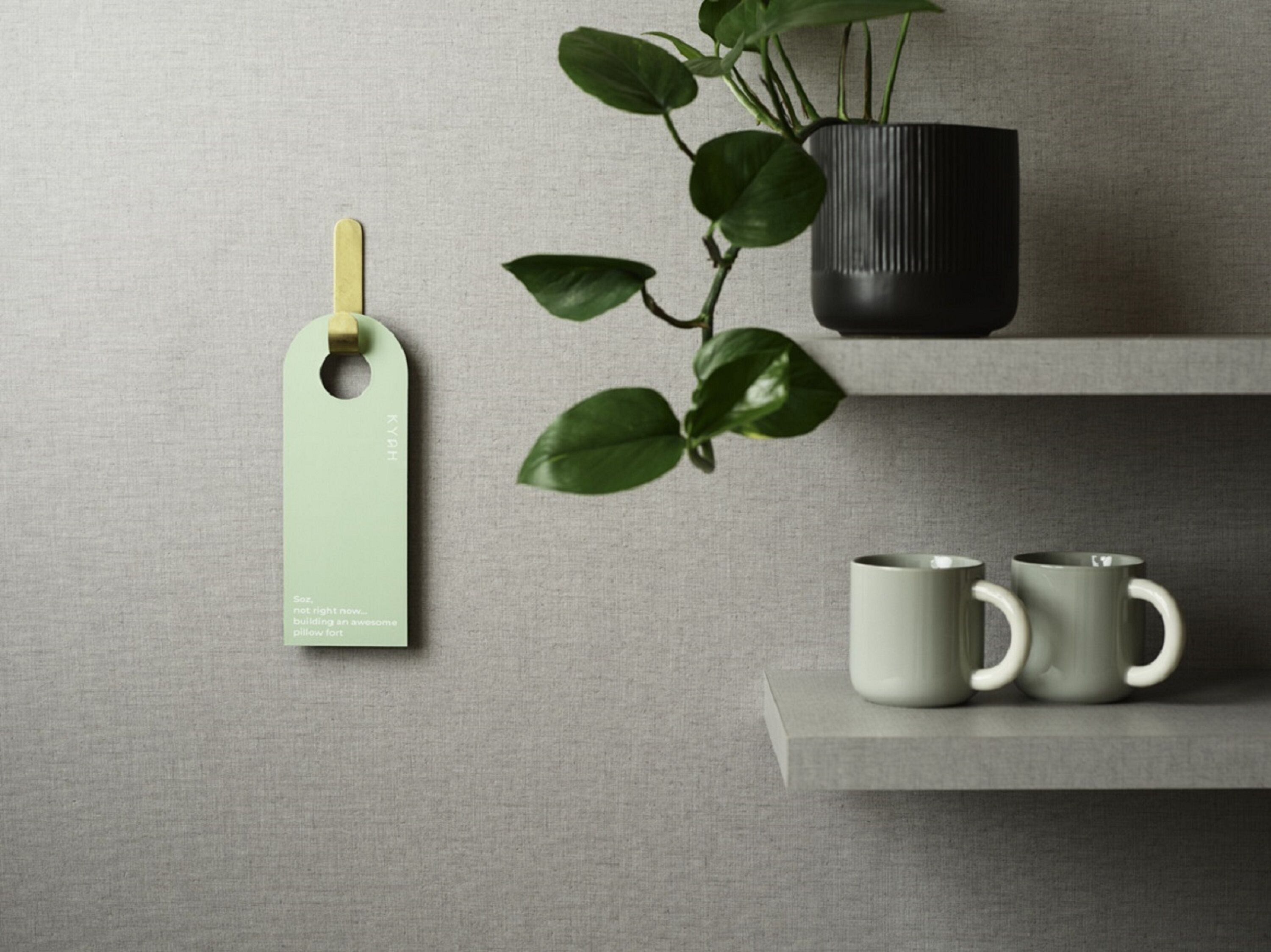 Una etiqueta con texto, una planta en maceta y dos tazas sobre una estantería.