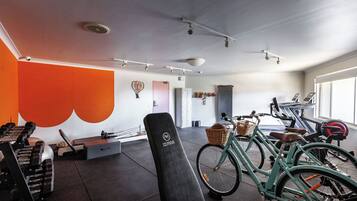 A gym with exercise equipment, a bench, and bicycles.