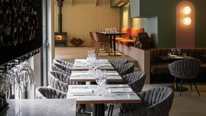 A restaurant with a long table set for dining, a fireplace, and a cozy seating area with cushions. - Kyah Hotel (Blackheath)